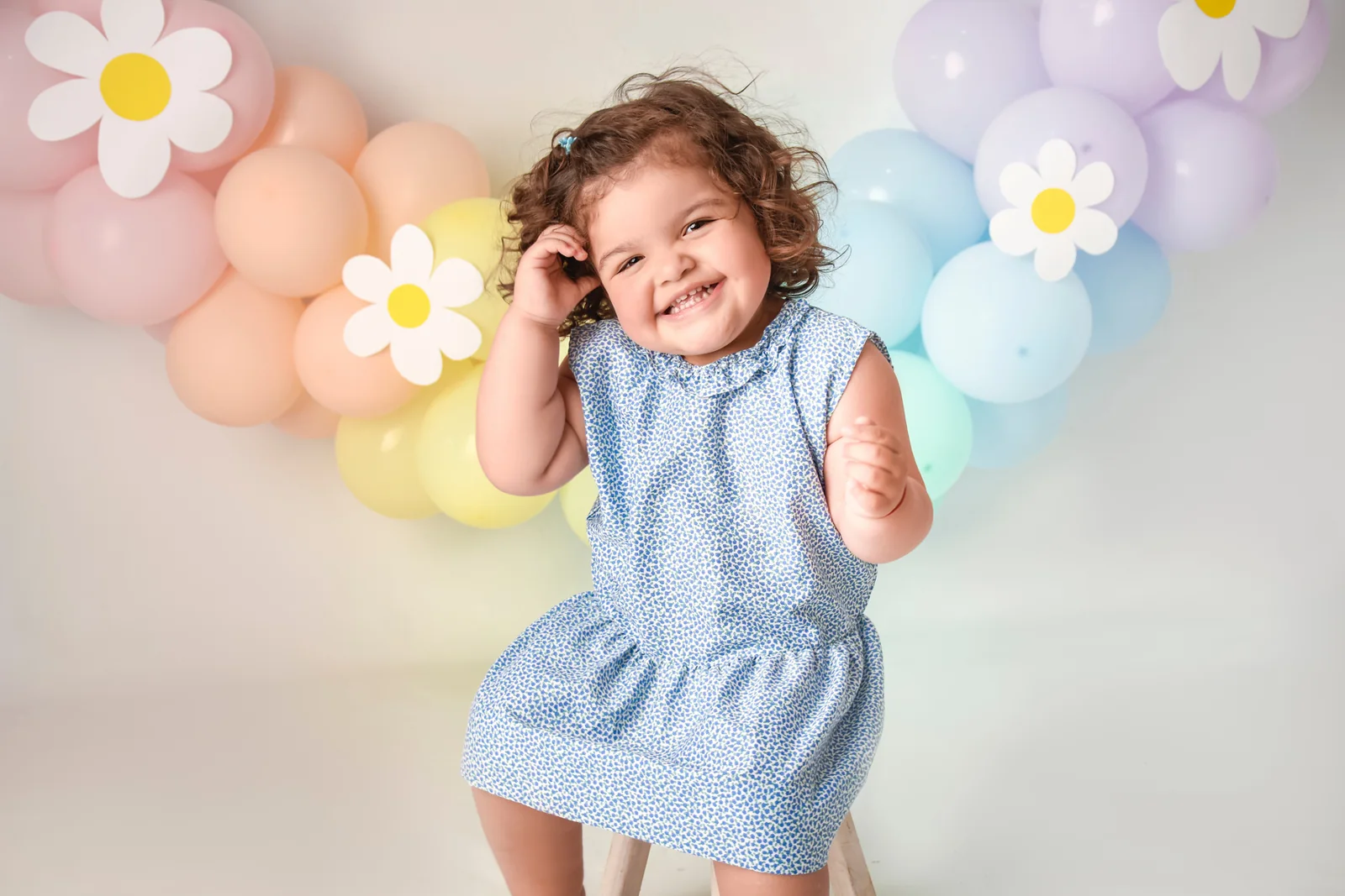 Nena sonriendo delante de una guirnalda de globos con margaritas