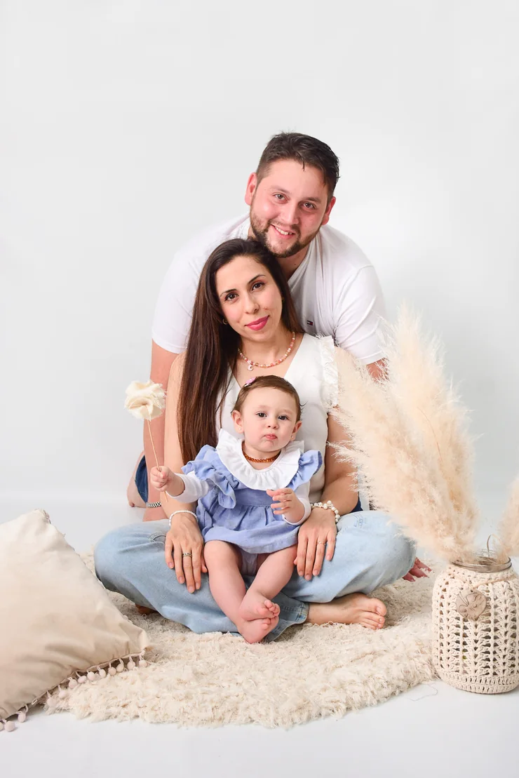 Familia sentada sobre almohadones en estudio de fondo claro