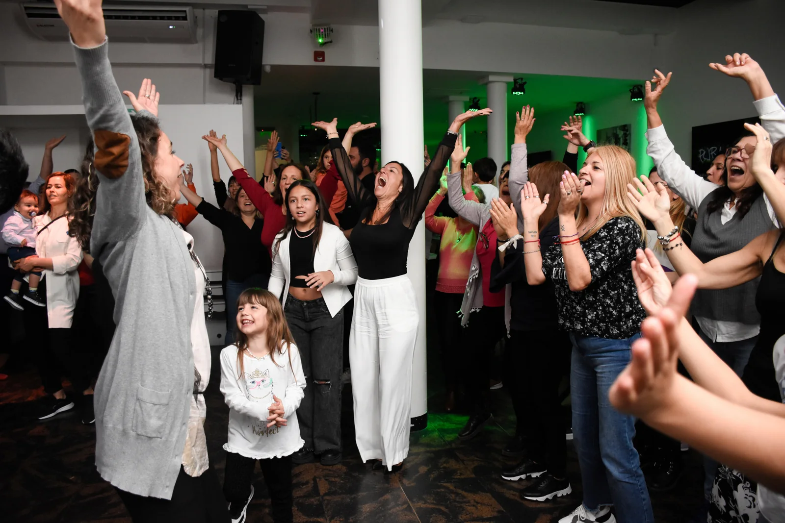 Invitados con los brazos en alto celebrando en la pista de baile