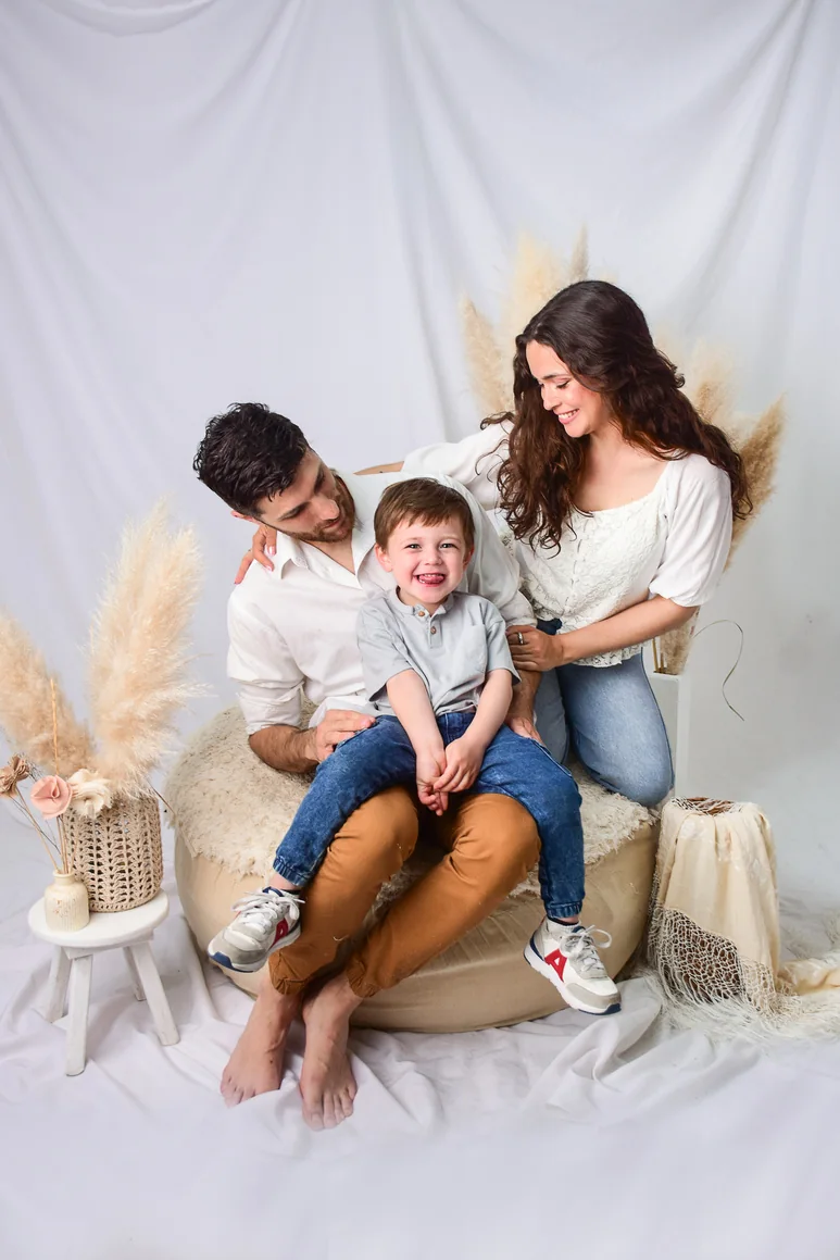 Papá, mamá y su hijo abrazados en estudio con pampas