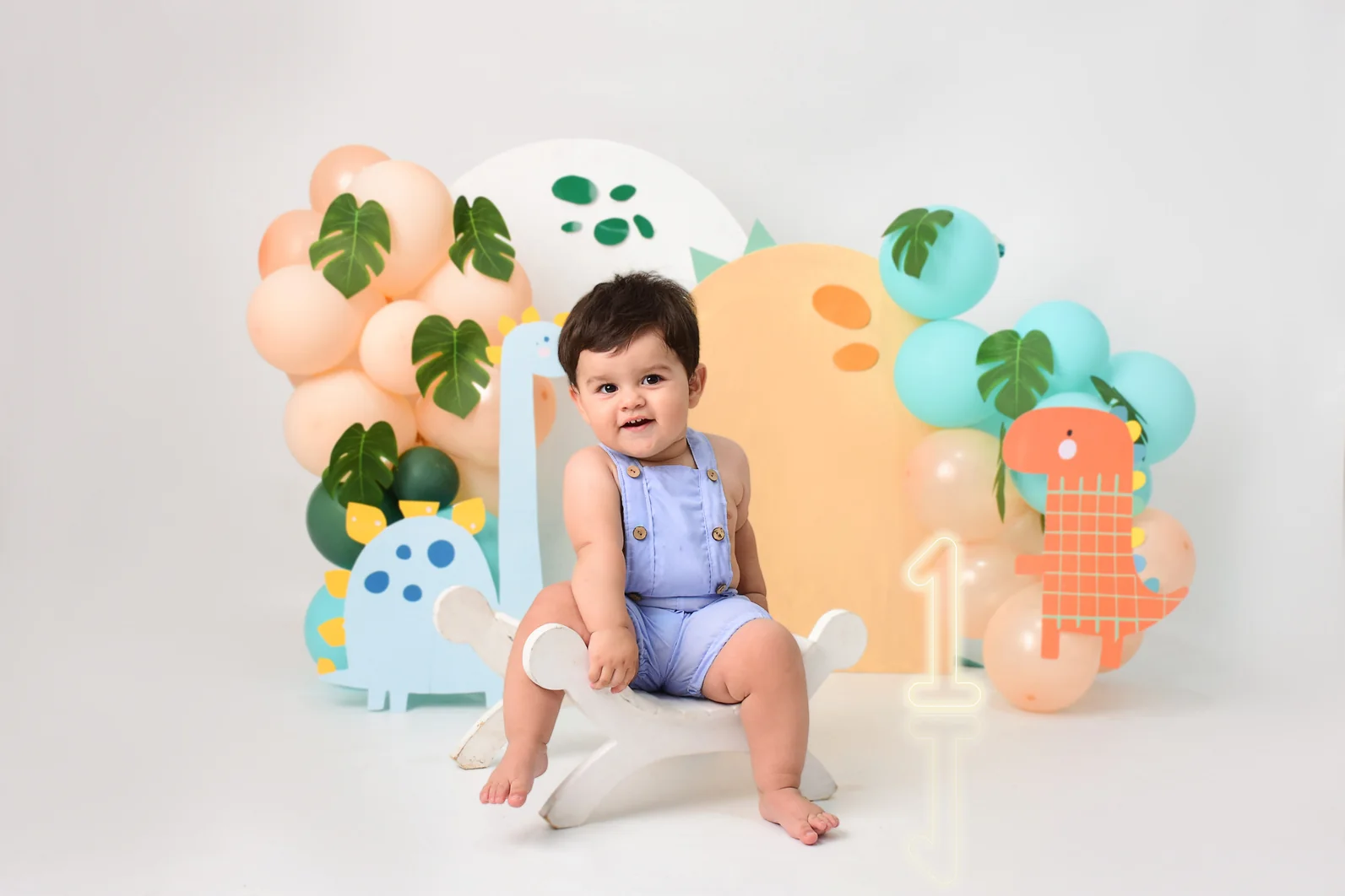 Bebé sentado en una banqueta con decoración en tonos durazno y verde agua